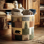Quilted patchwork storage basket with woodland forest design featuring pine trees and a bear, filled with folded blankets